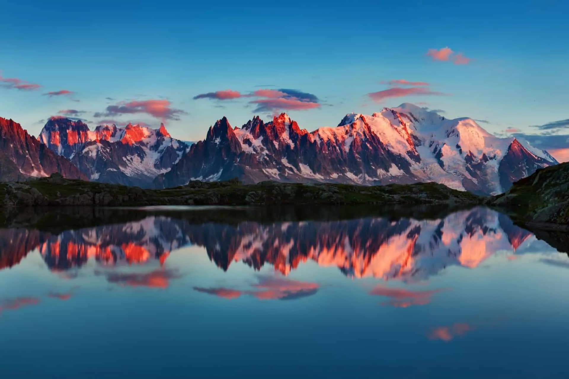 Mont Blanc massif mountains reflecting in alpine lake at sunrise or sunset