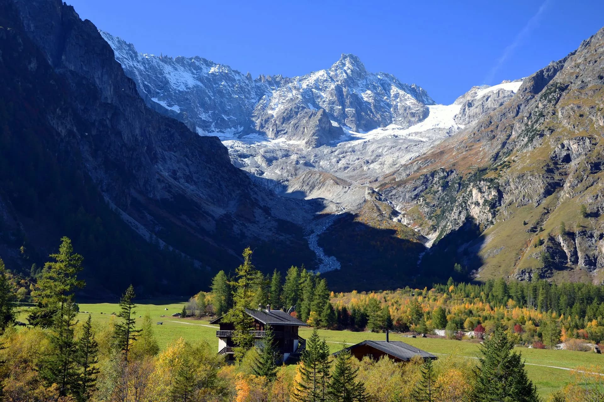 Alpine village of La Fouly in Val Ferret with snow-capped mountains and autumn trees.