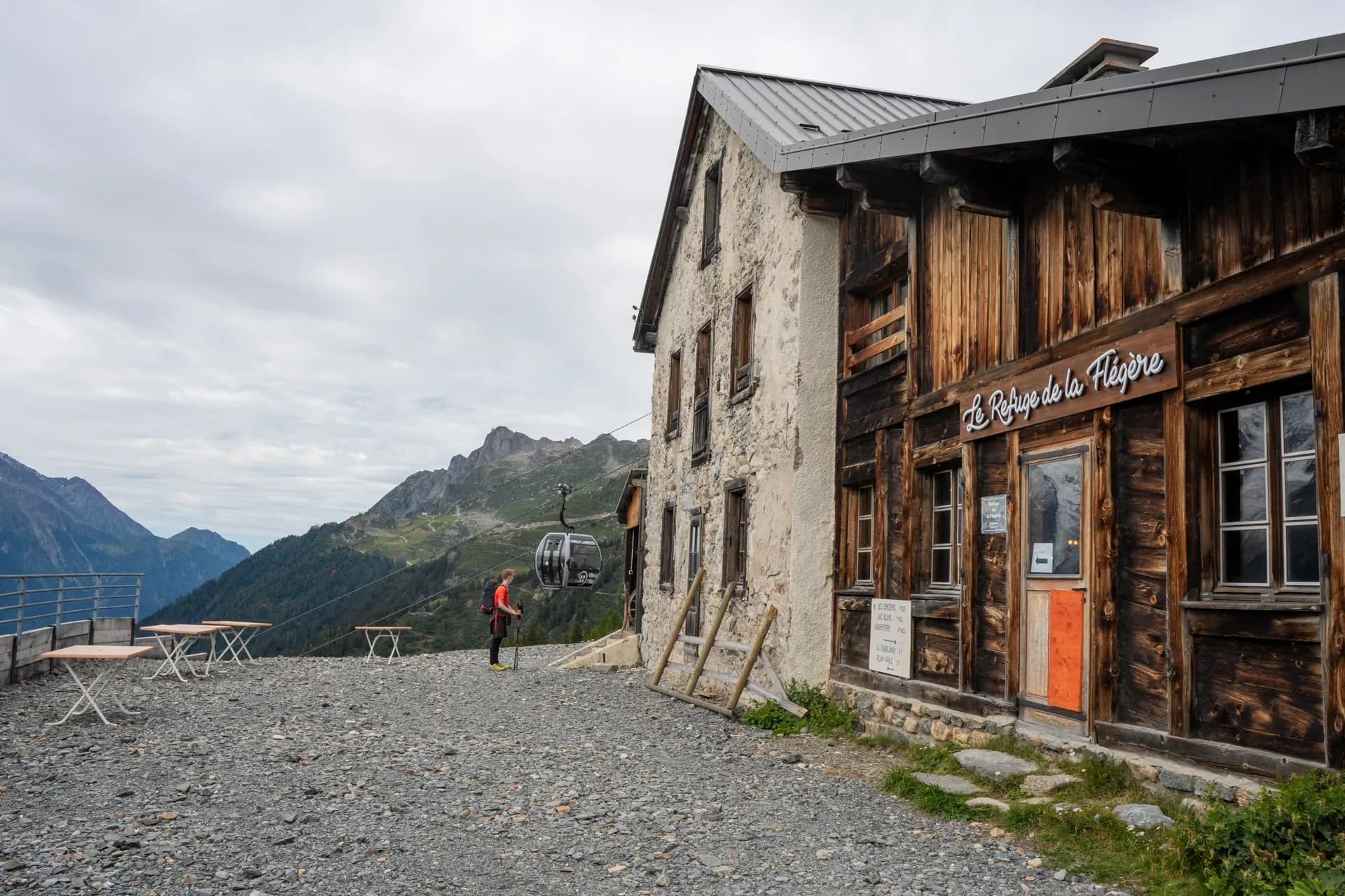 Cable car arriving at Le Refuge de la Flégère hut with hiker and mountains in Chamonix.