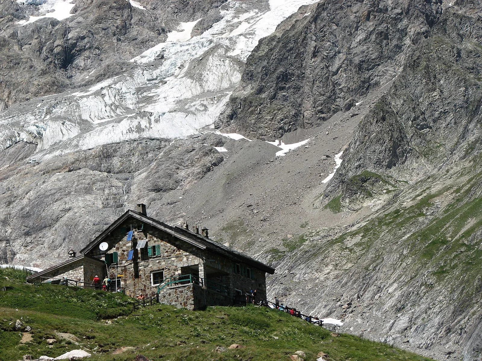 Stone mountain refuge, Rifugio Elisabetta, below a large glacier on rocky slopes