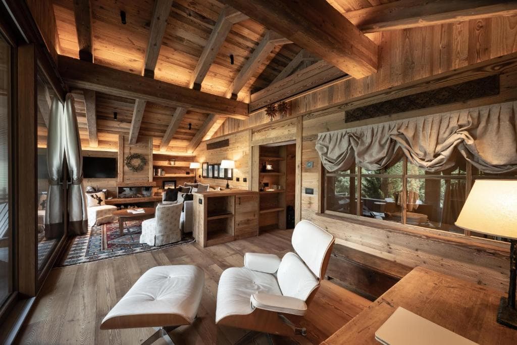 Luxurious wooden chalet interior with white lounge chair and fireplace area