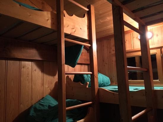 Wooden bunk beds with green bedding inside a dimly lit refuge cabin near Lac Blanc.