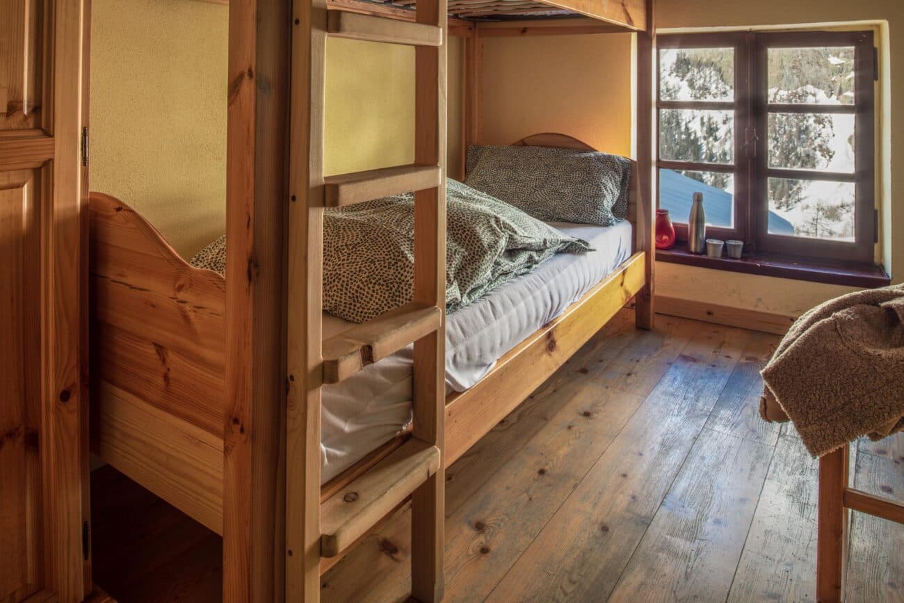 Bunk bed room interior with wooden floors and a window showing snowy mountains, Rifugio Monte Bianco.