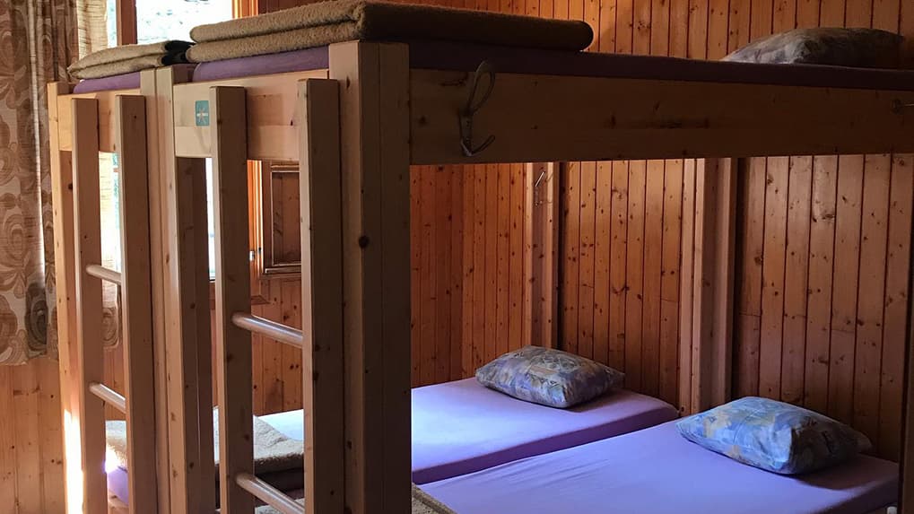 Wooden bunk beds with purple mattresses and pillows in a room with wood paneling.
