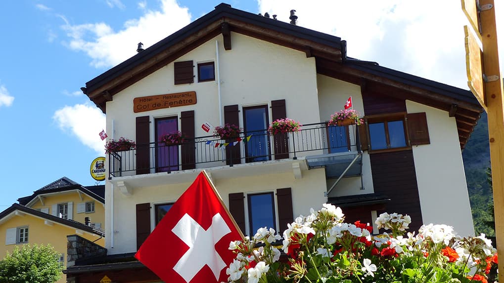 Hotel-Restaurant Col de Fenêtre building with Swiss flag and window boxes of flowers.