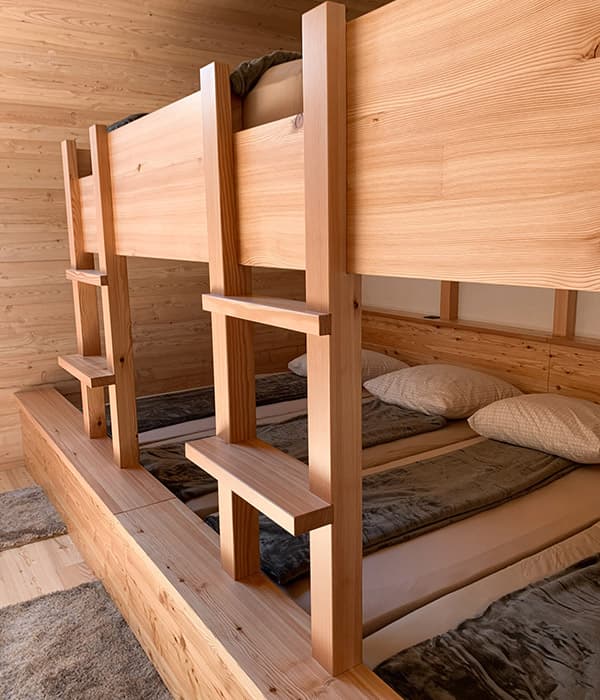 Wooden triple bunk beds with light wood paneling in a modern alpine room setting
