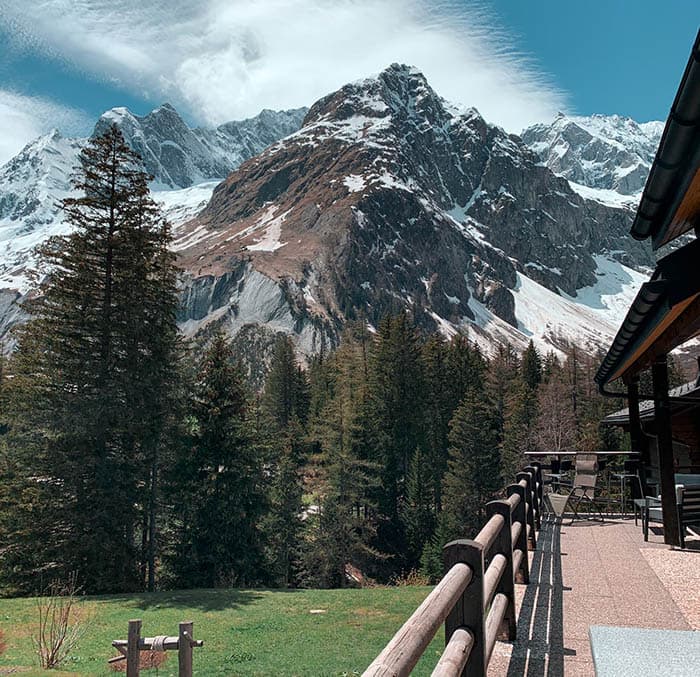 Gîte de la Fouly terrace view of snow-capped alpine mountains and pine forest