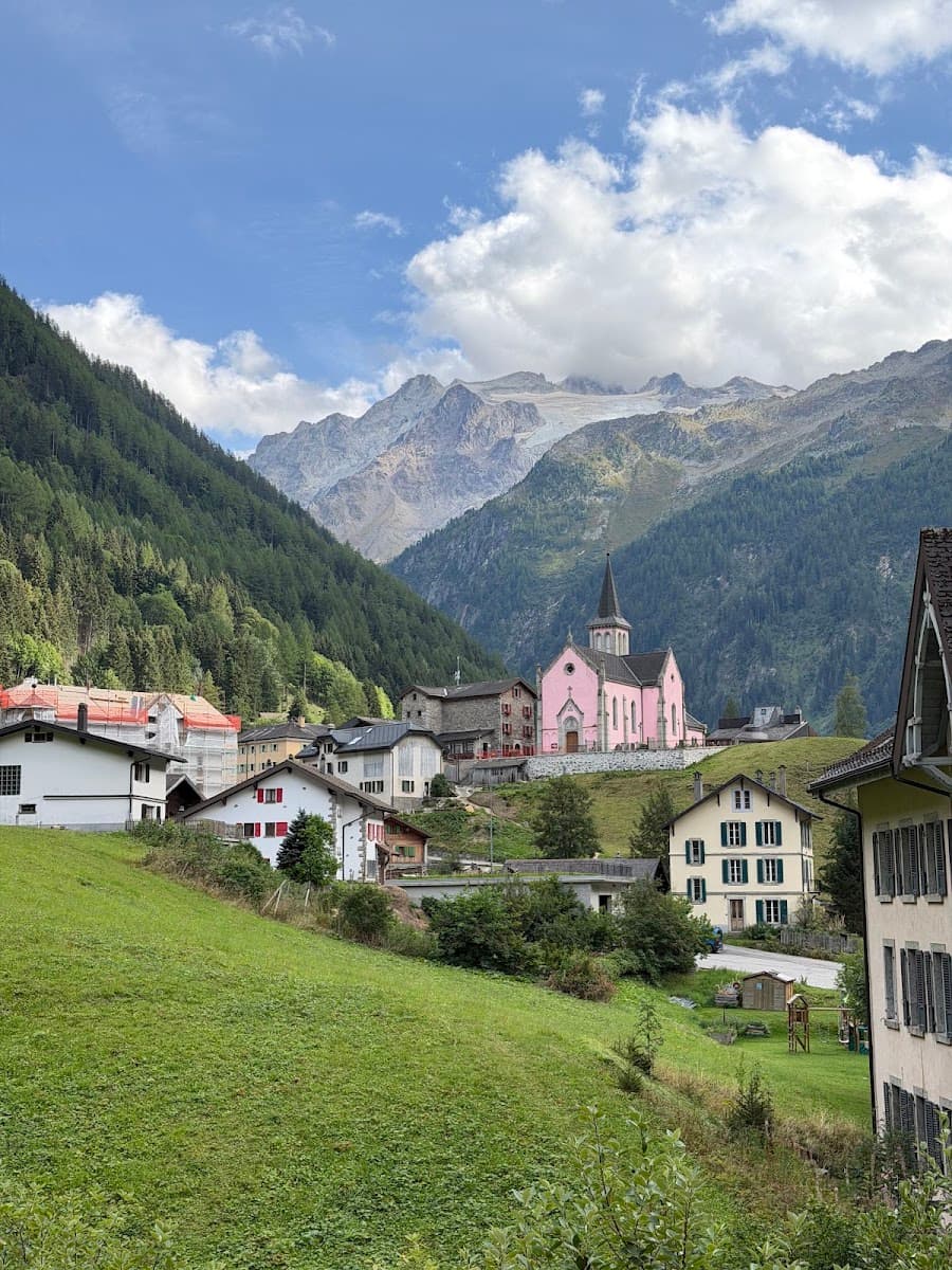 Alpine village with pink church and mountain peaks in background