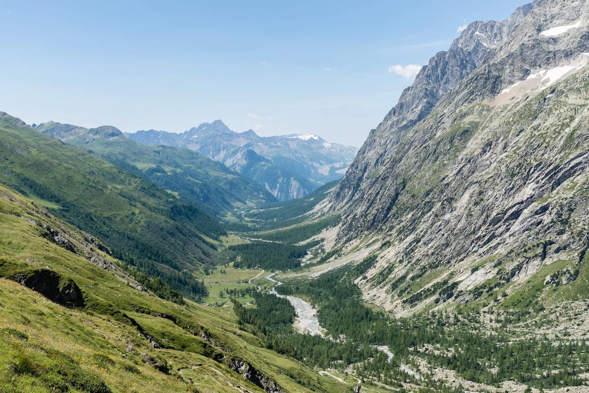 Alpine valley view of Ferret valley at Aosta with steep rocky slopes and a winding river.