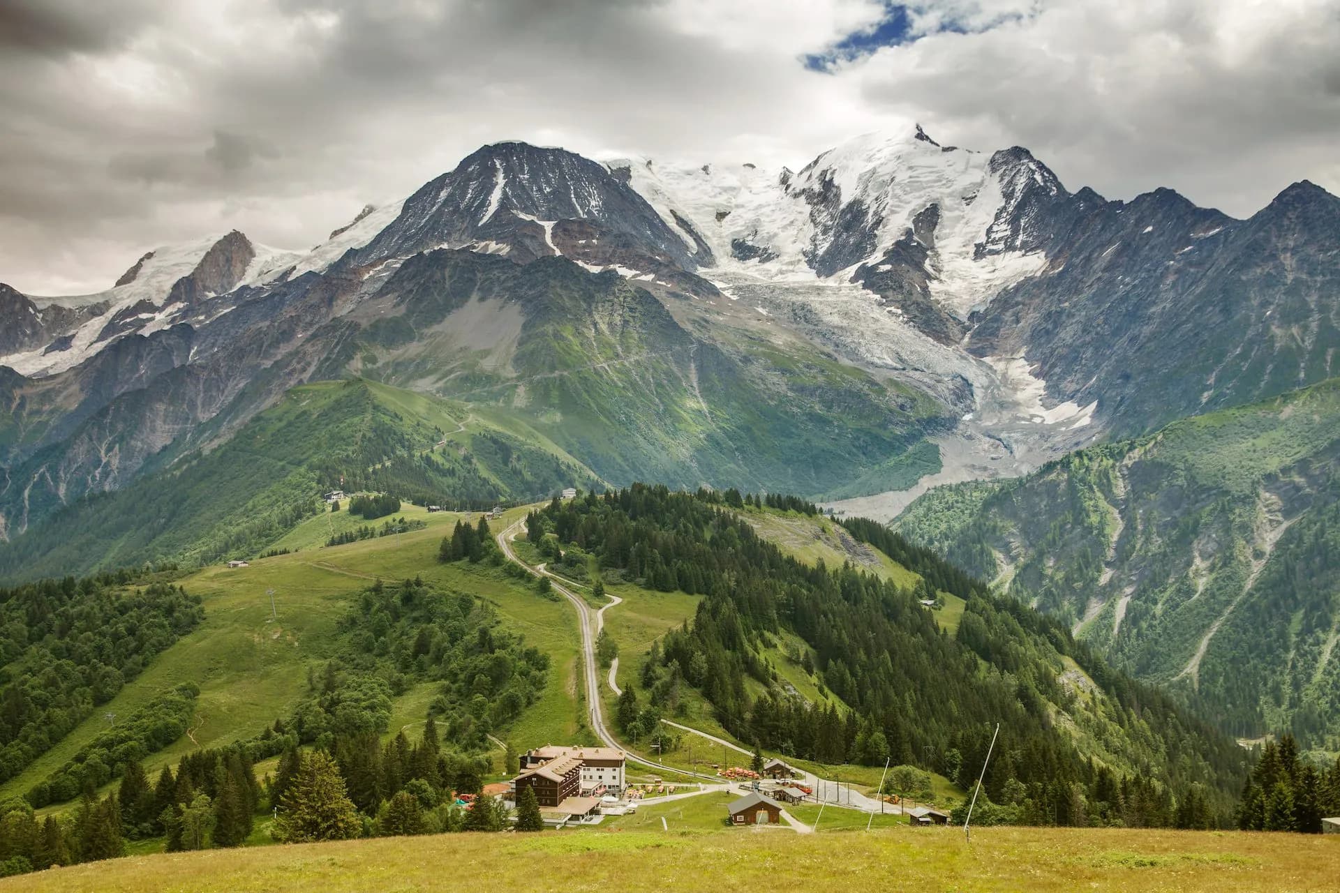 Mountain valley view with snow-capped peaks, hotel, and railway station in Les Houches.