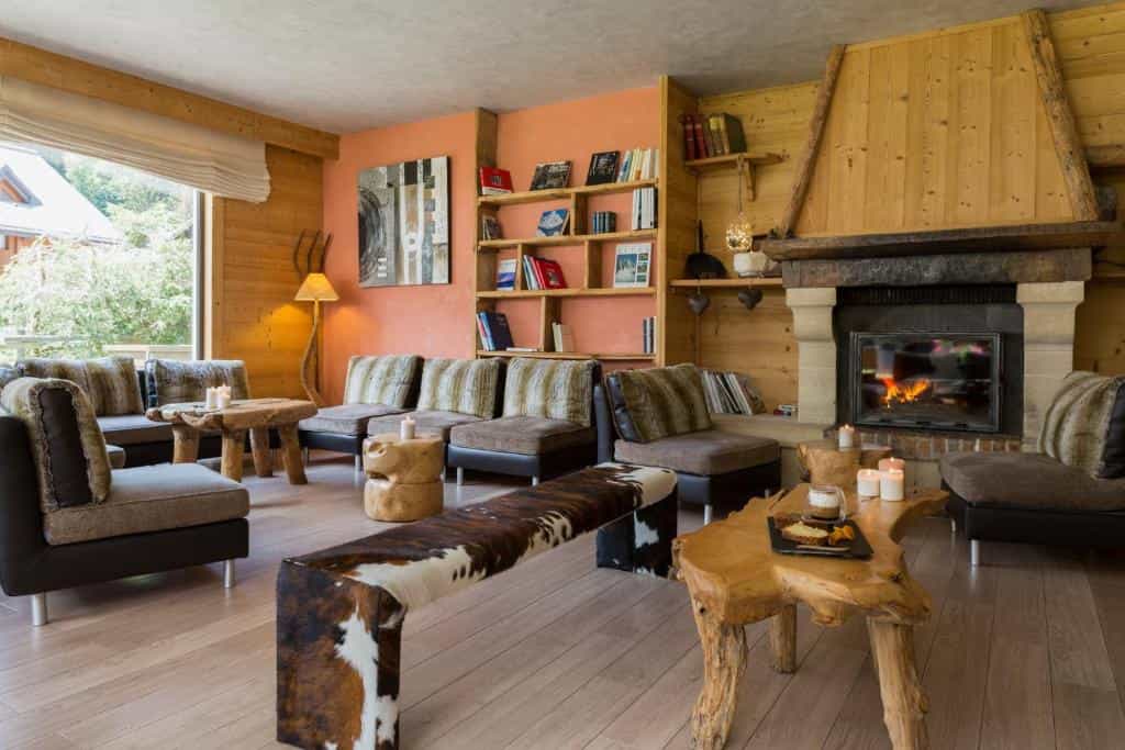 Lobby lounge with wood paneling, modern seating, and a lit stone fireplace, Hotel La Chémenaz.