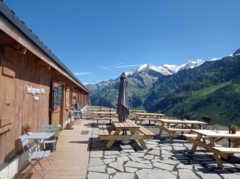 Outdoor dining terrace at Refuge des Prés with snow-capped mountains in the background