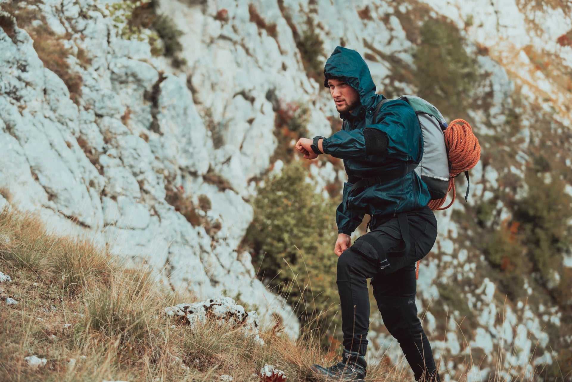 Un randonneur masculin regardant une montre de surveillance vérifiant son rythme cardiaque pendant la randonnée sur la montagne, voyage d'aventure extrême, sport de plein air, style de vie actif.