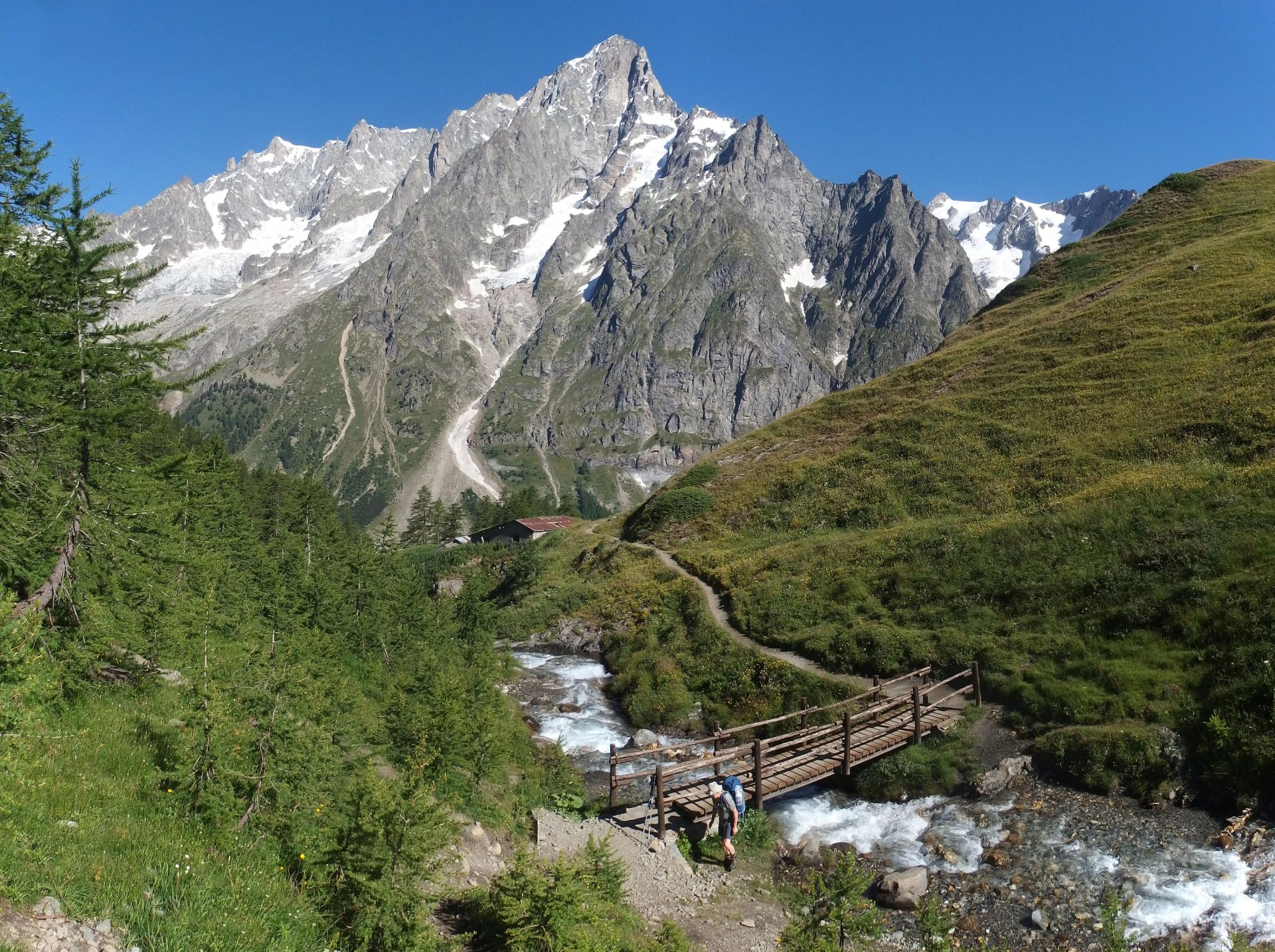 Alpy, Italia, Tour du Mont Blanc - a lo largo del macizo Mont de la Saxe, vista con un puente sobre el río