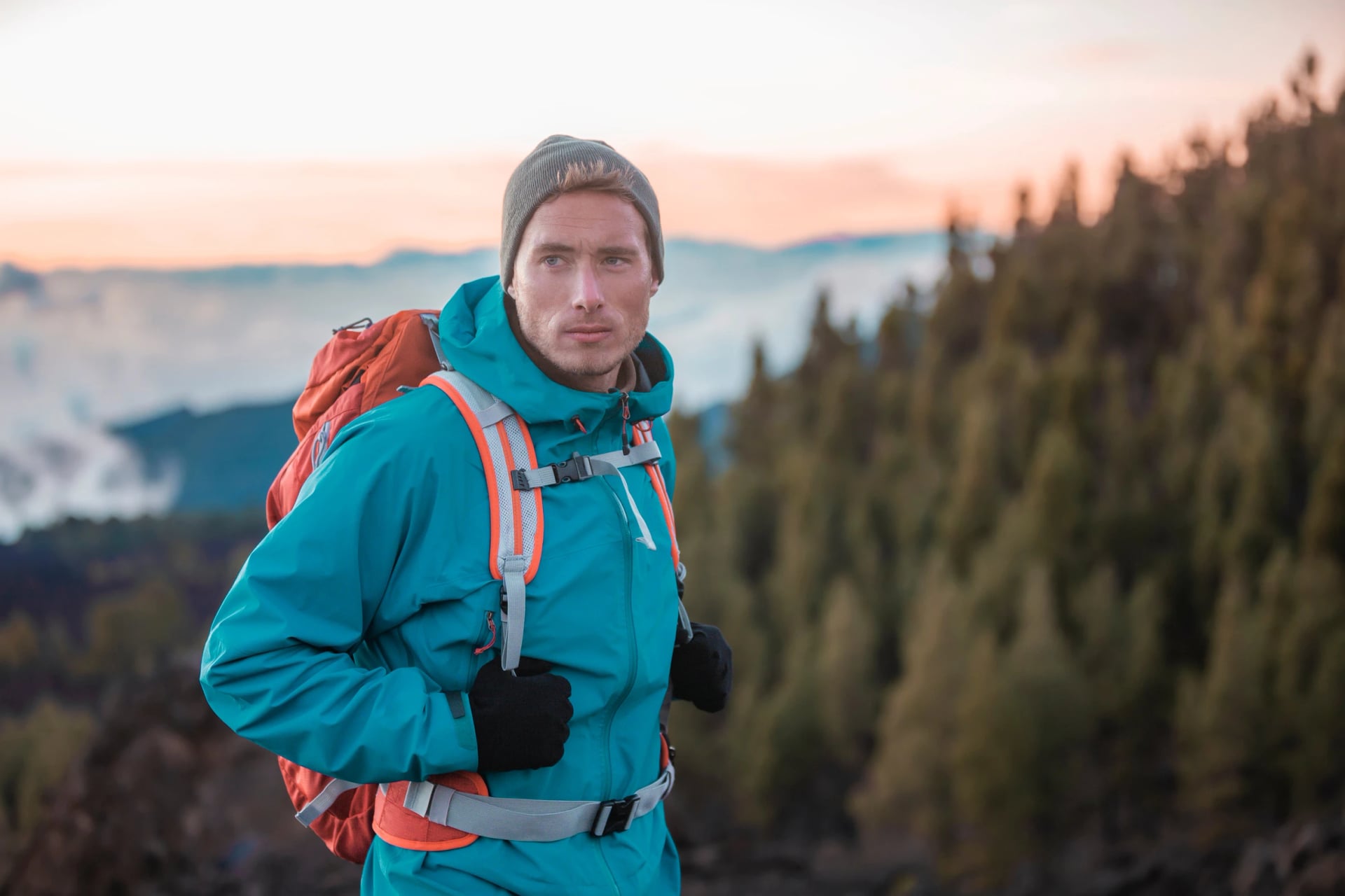 Man hiker hiking in mountain forest wearing cold weather accessories, wind jacket and backpack for camping outdoor. Guy portrait lifestyle.